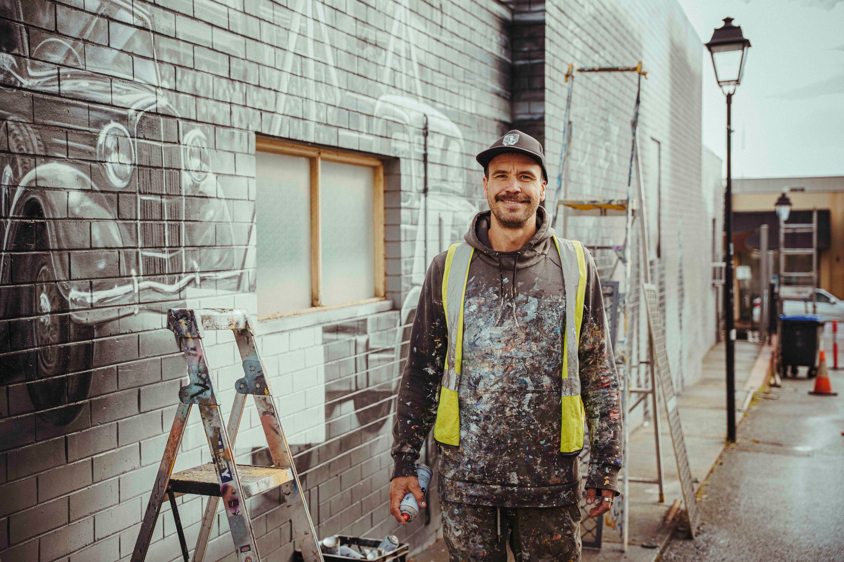 Jacob Butler, Shakey, beside the mural during painting.
